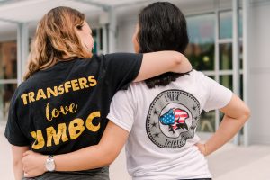 Students with their arms around each other wearing "Transfers love UMBC" and "UMBC Veterans" shirts
