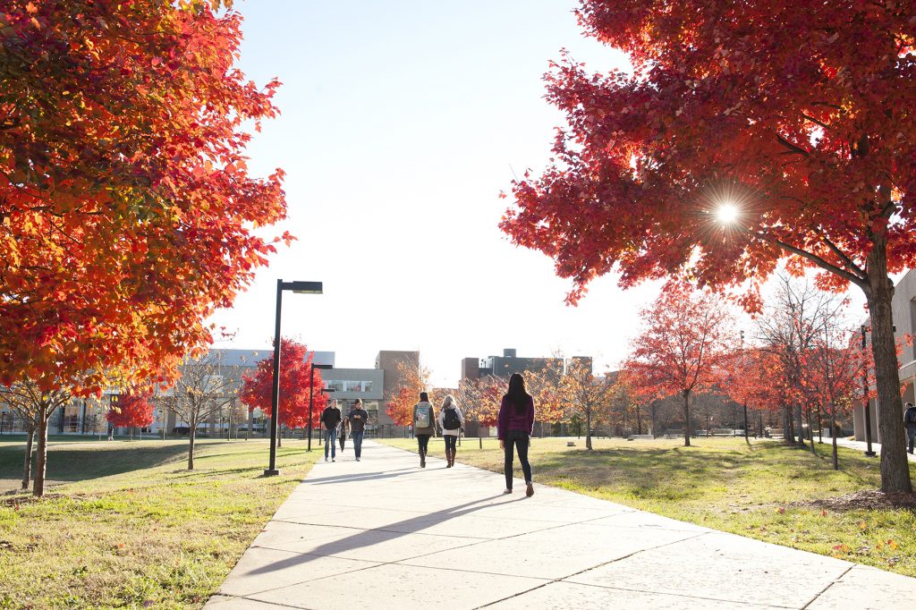 Students walking on campus at UMBC with colorful fall leaves on the trees