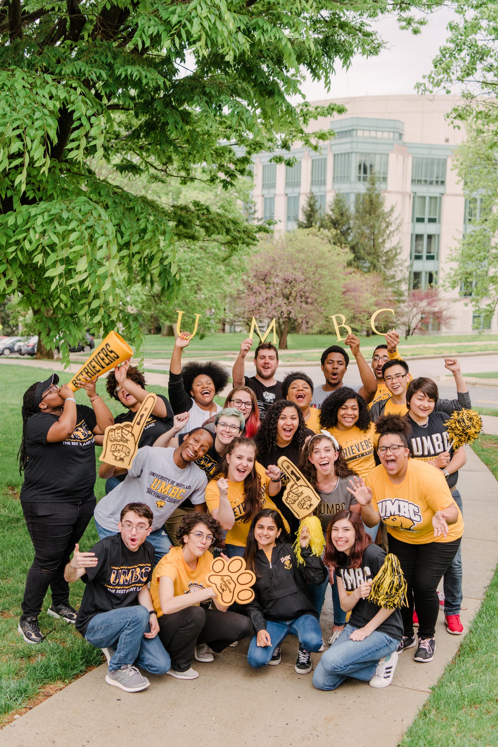 A diverse group of young men and women, joyfully showing their UMBC student community spirit.