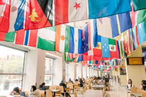 UMBC's Commons, featuring a ceiling full of flags from different countries, and students studying and eating at tables.